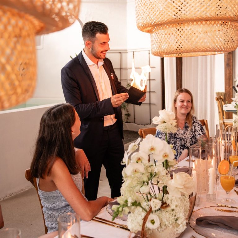 Ein elegantes Abendessen mit Kerzen, Blumen und einem Mann, der spricht.
